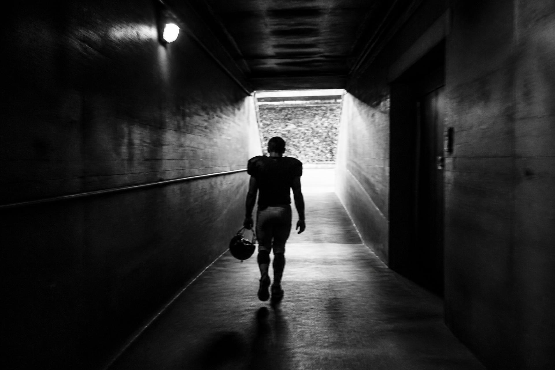Athlete walking alone through a stadium tunnel toward the light